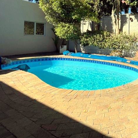The real kidney-shaped pool at the house, with brick paving and garden trees